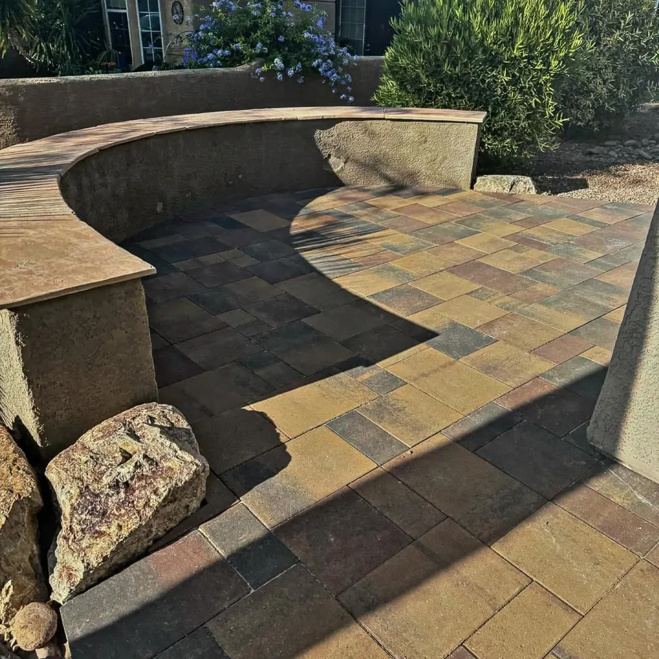 Curved stucco seat wall around a patio of mixed earth-tone pavers.