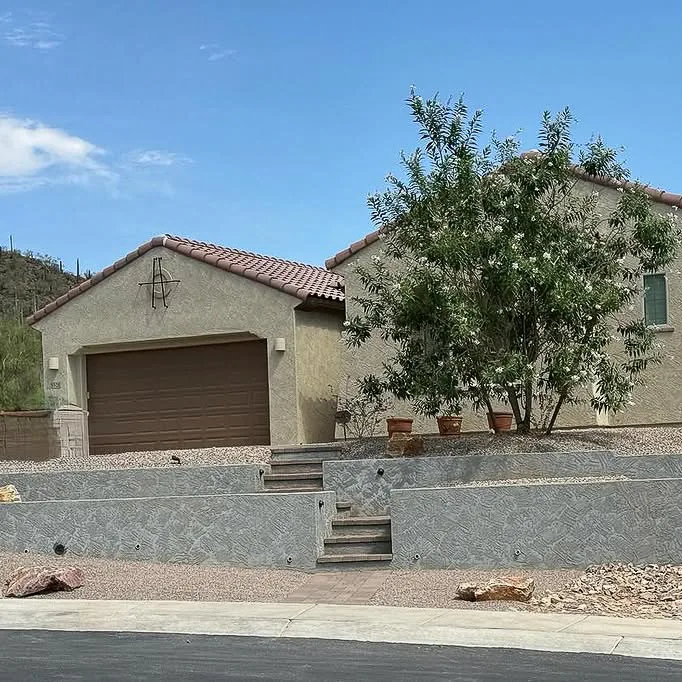 Tiered stucco walls and steps in a gravel front yard.