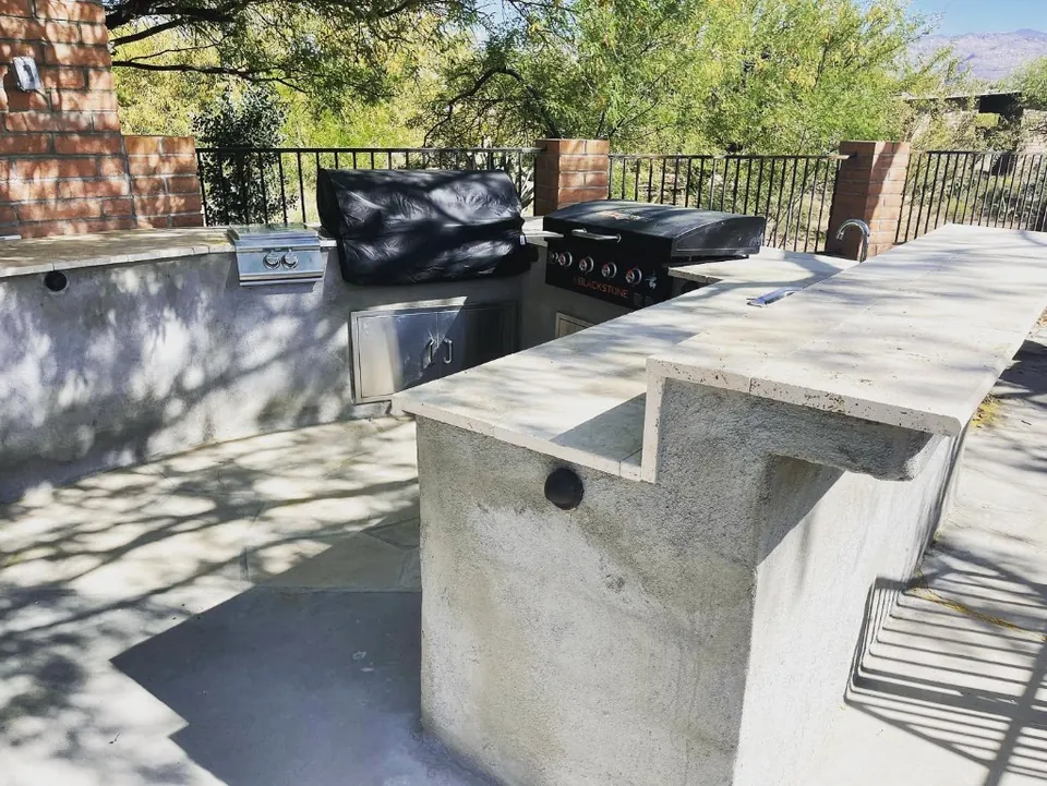 Outdoor kitchen counter with a raised bar, built-in grill, and griddle.