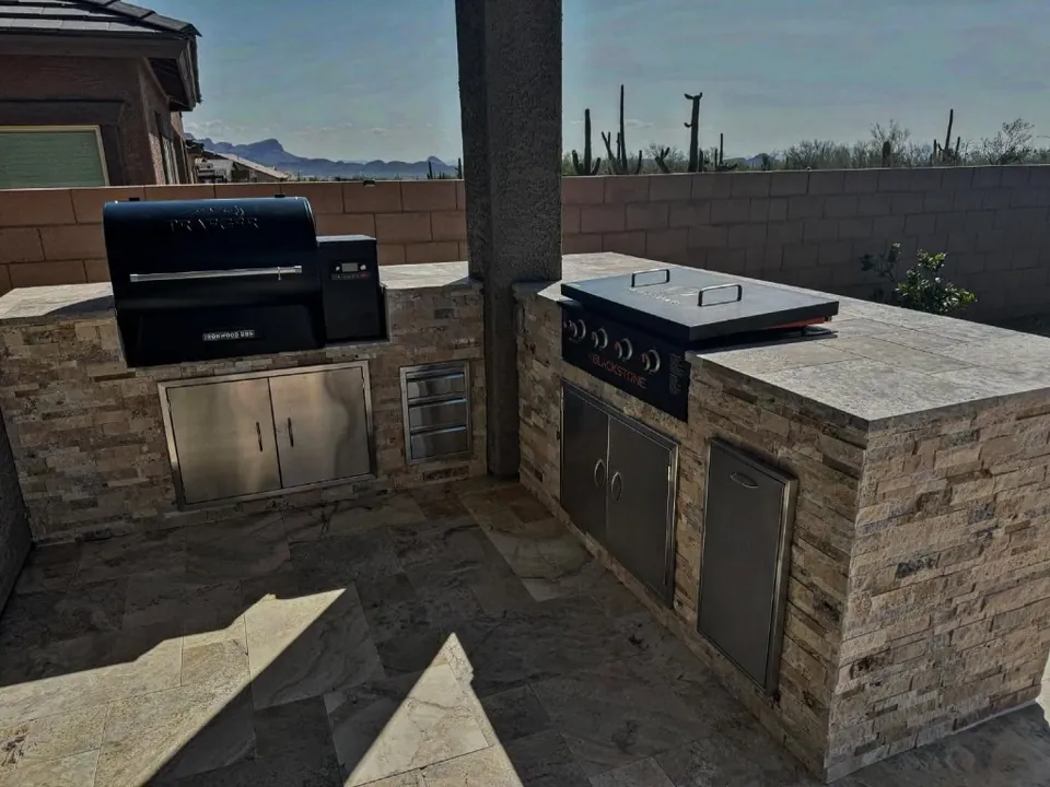 Stacked-stone outdoor kitchen with a pellet grill and built-in griddle.