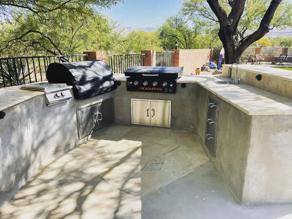 U-shaped outdoor kitchen with a built-in grill, side burner, griddle, and sink.